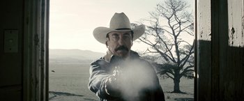 Movie still from “Red Hill” (2010), directed by Patrick Hughes – A man wearing a cowboy hat is holding a gun; Close Up shot, Low angle