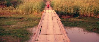 Movie still from “Red Sorghum” (1988), directed by Yimou Zhang – A person walking across a bridge over a river; Extreme Wide shot, High angle