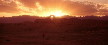 Movie still from “Red Sorghum” (1988), directed by Yimou Zhang – A person standing on a dirt field near a rock formation; Extreme Wide shot, Low angle