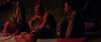 Movie still from “Red Sorghum” (1988), directed by Yimou Zhang – Two men sitting on the ground in a room; Medium shot, High angle