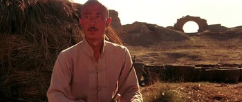Movie still from “Red Sorghum” (1988), directed by Yimou Zhang – A man in a tan shirt holding a sword in his hand; Close Up shot, Low angle