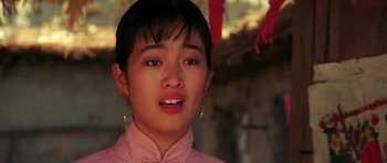 Movie still from “Red Sorghum” (1988), directed by Yimou Zhang – A young woman wearing a pink shirt and a pair of gold earrings; Close Up shot, Low angle