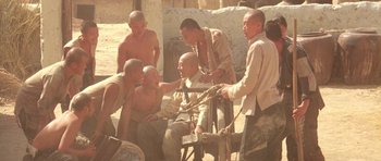 Movie still from “Red Sorghum” (1988), directed by Yimou Zhang – A group of men sitting in the dirt; Wide shot, High angle