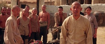 Movie still from “Red Sorghum” (1988), directed by Yimou Zhang – A group of men standing next to each other in the dirt; Medium shot, Low angle