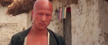 Movie still from “Red Sorghum” (1988), directed by Yimou Zhang – A man with a bald head is looking at the camera; Close Up shot, Low angle