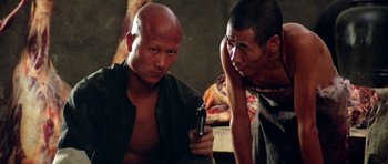 Movie still from “Red Sorghum” (1988), directed by Yimou Zhang – A man holding a gun next to another man; Close Up shot, High angle