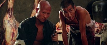 Movie still from “Red Sorghum” (1988), directed by Yimou Zhang – Two asian men are posing for a picture; Medium shot, Low angle
