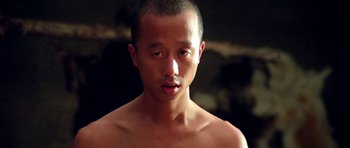Movie still from “Red Sorghum” (1988), directed by Yimou Zhang – A man with no shirt is looking at the camera; Close Up shot, Low angle