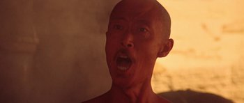Movie still from “Red Sorghum” (1988), directed by Yimou Zhang – A man with a bald head is looking at the camera; Close Up shot, Low angle