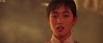 Movie still from “Red Sorghum” (1988), directed by Yimou Zhang – A young woman wearing a white shirt and a pair of dangling earrings; Close Up shot, Low angle