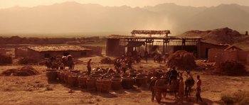 Movie still from “Red Sorghum” (1988), directed by Yimou Zhang – A group of people standing next to barrels on a dirt field; Extreme Wide shot, High angle