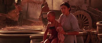 Movie still from “Red Sorghum” (1988), directed by Yimou Zhang – A woman and a child in bathing suits sit on steps in front of a fountain; Medium shot, Low angle