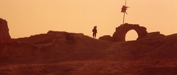 Movie still from “Red Sorghum” (1988), directed by Yimou Zhang – A person standing on top of a dirt hill; Extreme Wide shot, Low angle