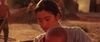 Movie still from “Red Sorghum” (1988), directed by Yimou Zhang – A young woman holding an apple in her hands; Close Up shot, High angle