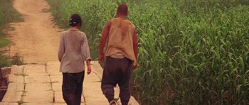 Movie still from “Red Sorghum” (1988), directed by Yimou Zhang – A man and a woman walking down a sidewalk; Wide shot, Low angle