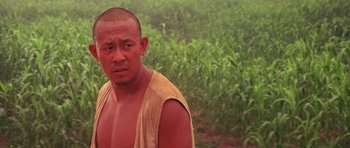 Movie still from “Red Sorghum” (1988), directed by Yimou Zhang – A man in a yellow shirt is standing in a field; Close Up shot, Low angle