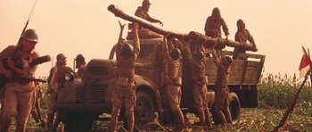Movie still from “Red Sorghum” (1988), directed by Yimou Zhang – A group of men holding a large log in front of an army truck; Wide shot, Low angle