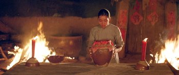 Movie still from “Red Sorghum” (1988), directed by Yimou Zhang – A woman is holding a large bowl in a kitchen; Medium shot, Low angle
