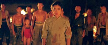 Movie still from “Red Sorghum” (1988), directed by Yimou Zhang – A group of people standing in a dark room; Medium shot, Over the shoulder angle