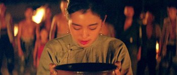 Movie still from “Red Sorghum” (1988), directed by Yimou Zhang – A woman is holding a plate in front of her face; Close Up shot, Low angle