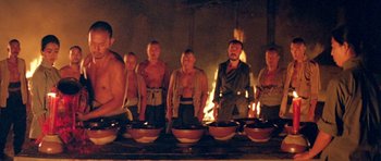 Movie still from “Red Sorghum” (1988), directed by Yimou Zhang – A group of men standing around a fire; Medium shot, Low angle