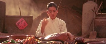 Movie still from “Red Sorghum” (1988), directed by Yimou Zhang – A woman sitting in front of a turkey on top of a table; Close Up shot, Over the shoulder angle