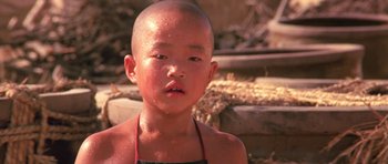 Movie still from “Red Sorghum” (1988), directed by Yimou Zhang – A little boy with a shaved head is looking into the camera; Close Up shot, Low angle