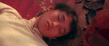 Movie still from “Red Sorghum” (1988), directed by Yimou Zhang – A young girl sleeping on the ground with her eyes closed; Close Up shot, Overhead angle