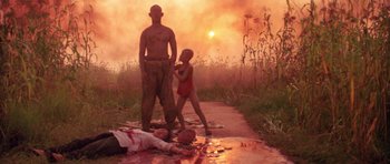 Movie still from “Red Sorghum” (1988), directed by Yimou Zhang – A man and a child standing next to a dead body on the side of the road; Wide shot, Low angle