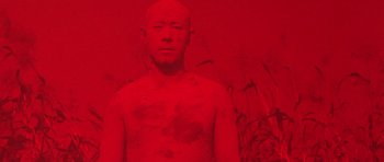 Movie still from “Red Sorghum” (1988), directed by Yimou Zhang – A man in a red room with his face covered in red paint; Medium shot, Overhead angle