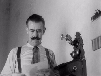 Movie still from “Redes” (1936), directed by Fred Zinnemann – A man in a tie and suspenders standing next to an old phone; Close Up shot, Low angle
