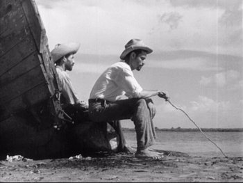 Movie still from “Redes” (1936), directed by Fred Zinnemann – Two men sitting on the shore of a body of water; Wide shot, Low angle