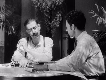Movie still from “Redes” (1936), directed by Fred Zinnemann – Two men are sitting at a table and talking; Medium shot, Over the shoulder angle