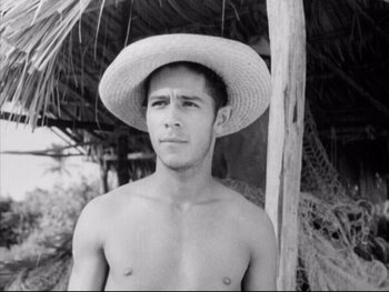 Movie still from “Redes” (1936), directed by Fred Zinnemann – A shirtless man wearing a straw hat in front of a wooden pole; Close Up shot, Low angle