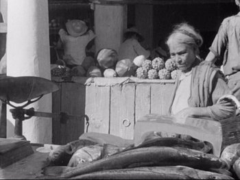 Movie still from “Redes” (1936), directed by Fred Zinnemann – An older woman sitting in front of a fruit stand; Medium shot, High angle