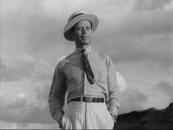 Movie still from “Redes” (1936), directed by Fred Zinnemann – A man wearing a hat and a tie standing in front of a mountain; Medium shot, Low angle
