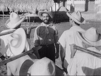 Movie still from “Redes” (1936), directed by Fred Zinnemann – An old photo of a man standing in front of a group of men; Medium shot, Over the shoulder angle
