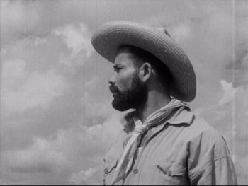 Movie still from “Redes” (1936), directed by Fred Zinnemann – A man wearing a cowboy hat standing in front of a cloudy sky; Medium shot, Low angle