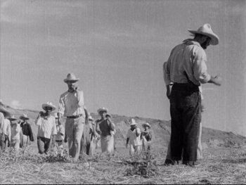 Movie still from “Redes” (1936), directed by Fred Zinnemann – A group of people in a field with hats on; Wide shot, Low angle