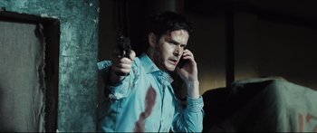 Movie still from “Redirected” (2014), directed by Emilis Velyvis – A man holding a cell phone up to his ear; Close Up shot, Over the shoulder angle