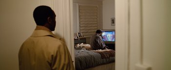 Movie still from “Reign Over Me” (2007), directed by Mike Binder – A man sitting on a bed watching television; Medium shot, High angle