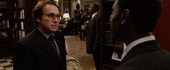 Movie still from “Reign Over Me” (2007), directed by Mike Binder – A man in a suit and tie in a room; Close Up shot, Over the shoulder angle