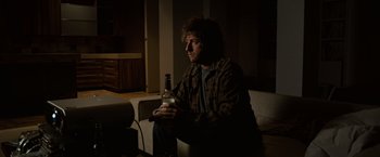 Movie still from “Reign Over Me” (2007), directed by Mike Binder – A man sitting on a couch holding a bottle of beer; Medium shot, High angle