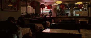 Movie still from “Reign Over Me” (2007), directed by Mike Binder – A restaurant with tables , chairs , and lights in the background; Wide shot, Over the shoulder angle