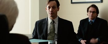 Movie still from “Reign Over Me” (2007), directed by Mike Binder – A man in a suit and tie sitting at a table; Close Up shot, Low angle