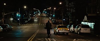Movie still from “Reign Over Me” (2007), directed by Mike Binder – A man riding a bike down the middle of a street at night; Extreme Wide shot, High angle