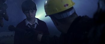 Movie still from “Reign of Fire” (2002), directed by Rob Bowman – A man wearing a yellow hard hat is looking at another man; Medium shot, Over the shoulder angle