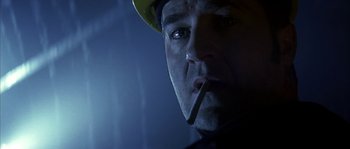 Movie still from “Reign of Fire” (2002), directed by Rob Bowman – A person wearing a hard hat smoking a cigarette; Close Up shot, Low angle