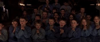 Movie still from “Reign of Fire” (2002), directed by Rob Bowman – A group of young boys sitting in front of each other with their hands clasped together; Medium shot, High angle