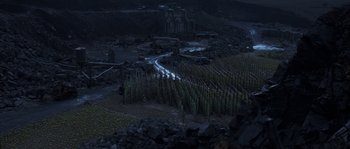 Movie still from “Reign of Fire” (2002), directed by Rob Bowman – A field with trees growing in the middle of it at night time; Extreme Wide shot, High angle